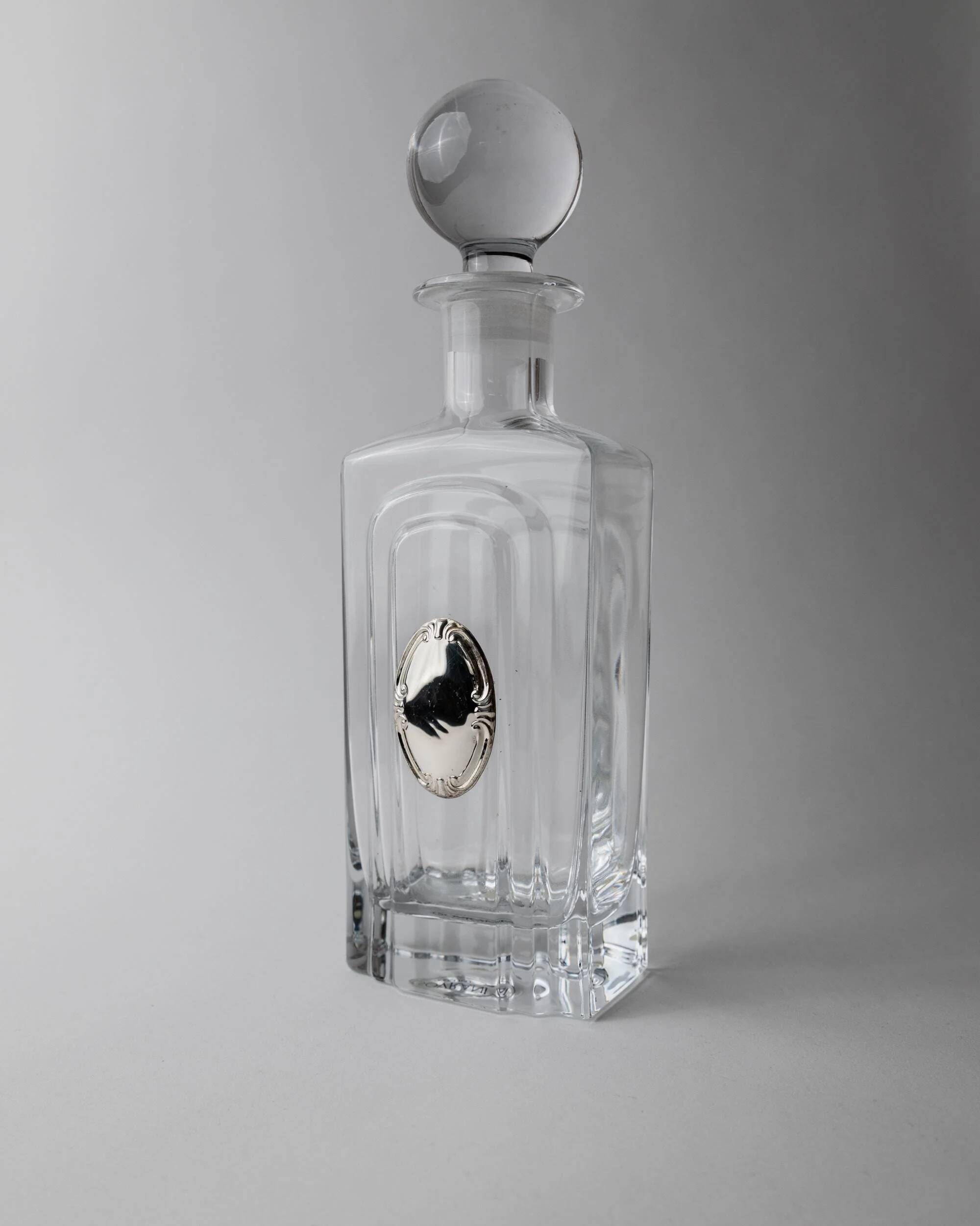 Vintage glass decanter from the 1980s, transparent glass with a silver plate and spherical stopper.
