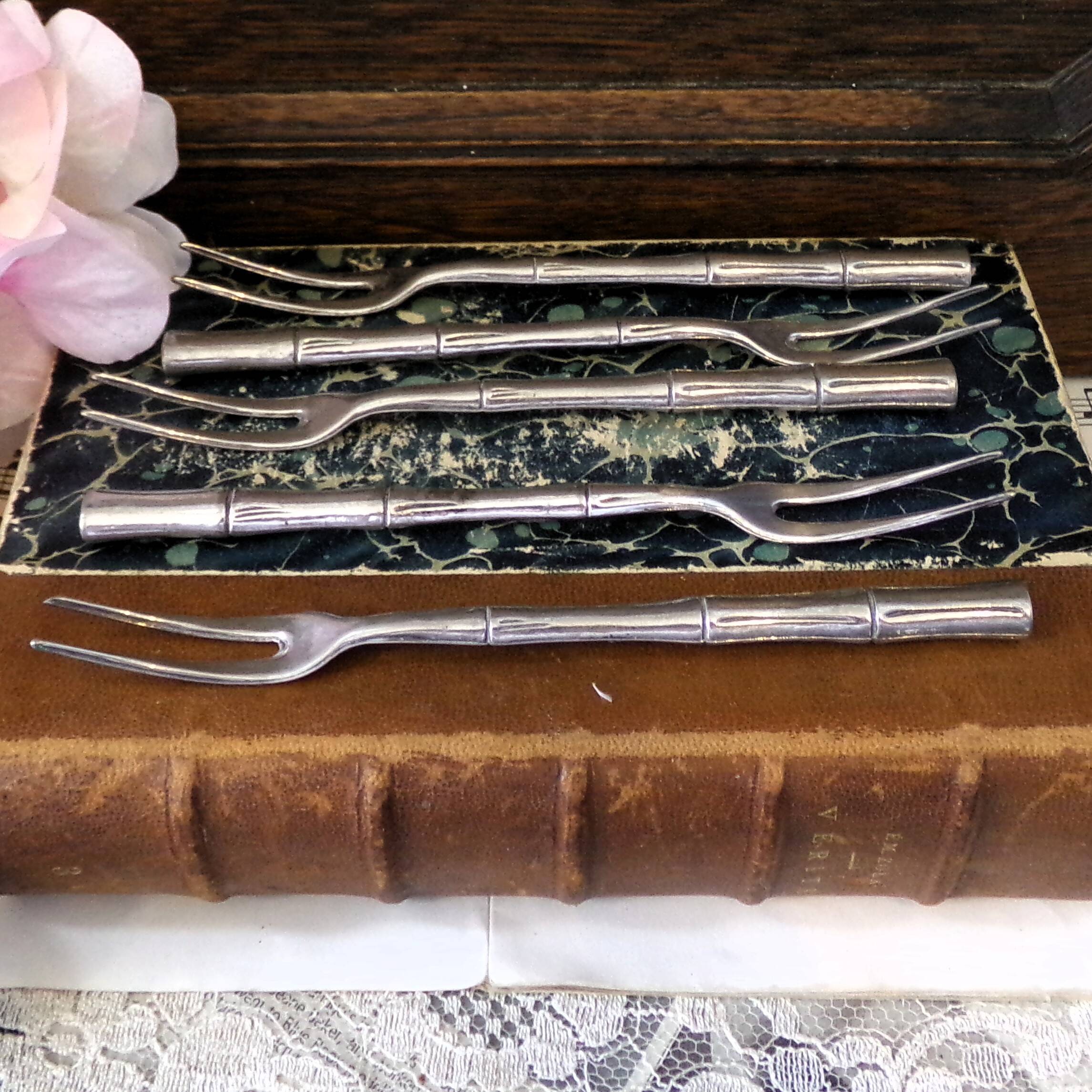 Five silver-plated metal appetizer forks with bamboo-style handles
