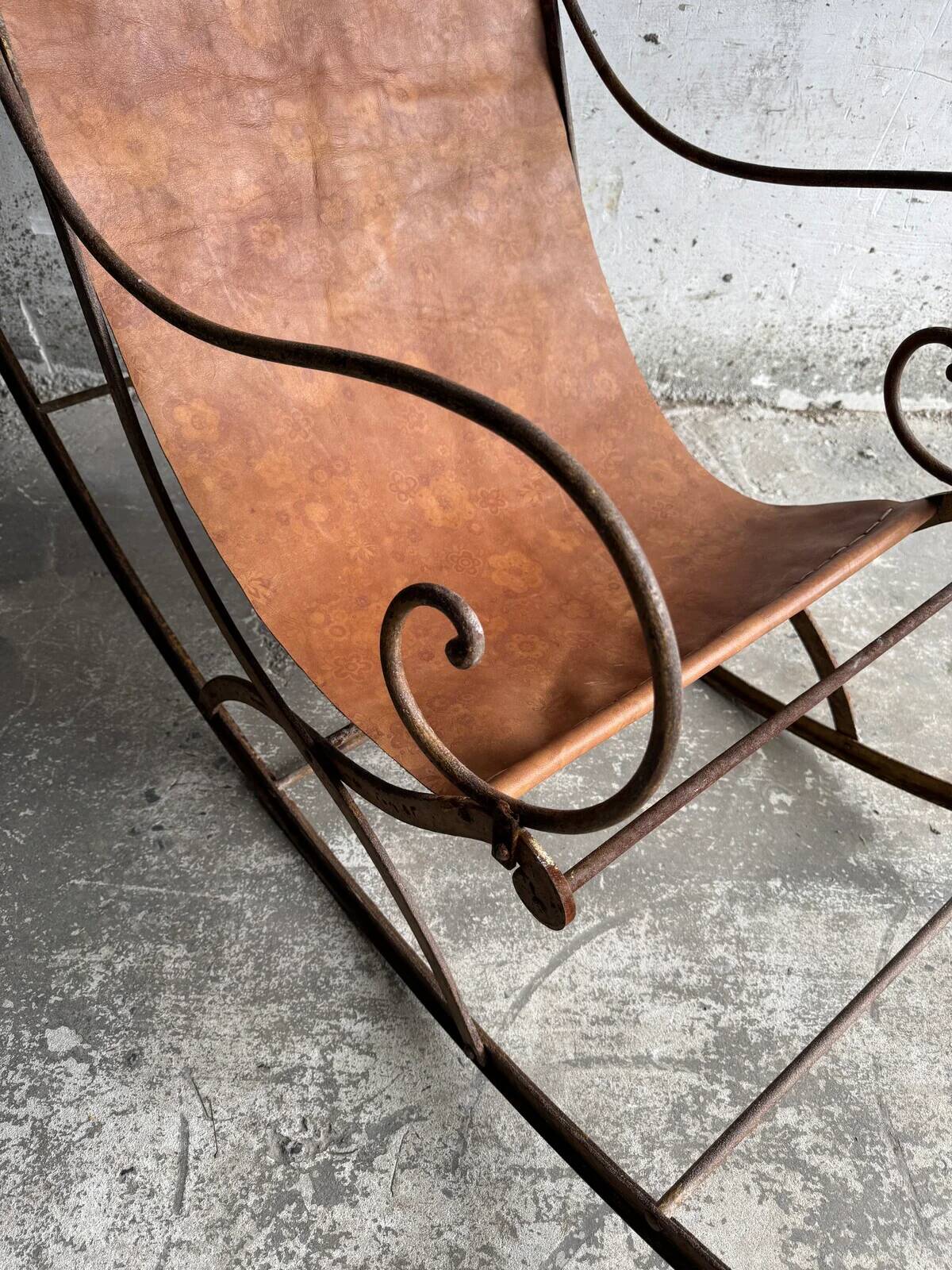 19th-century dark brown wrought-metal rocking chair with cognac leather sling seat, vintage