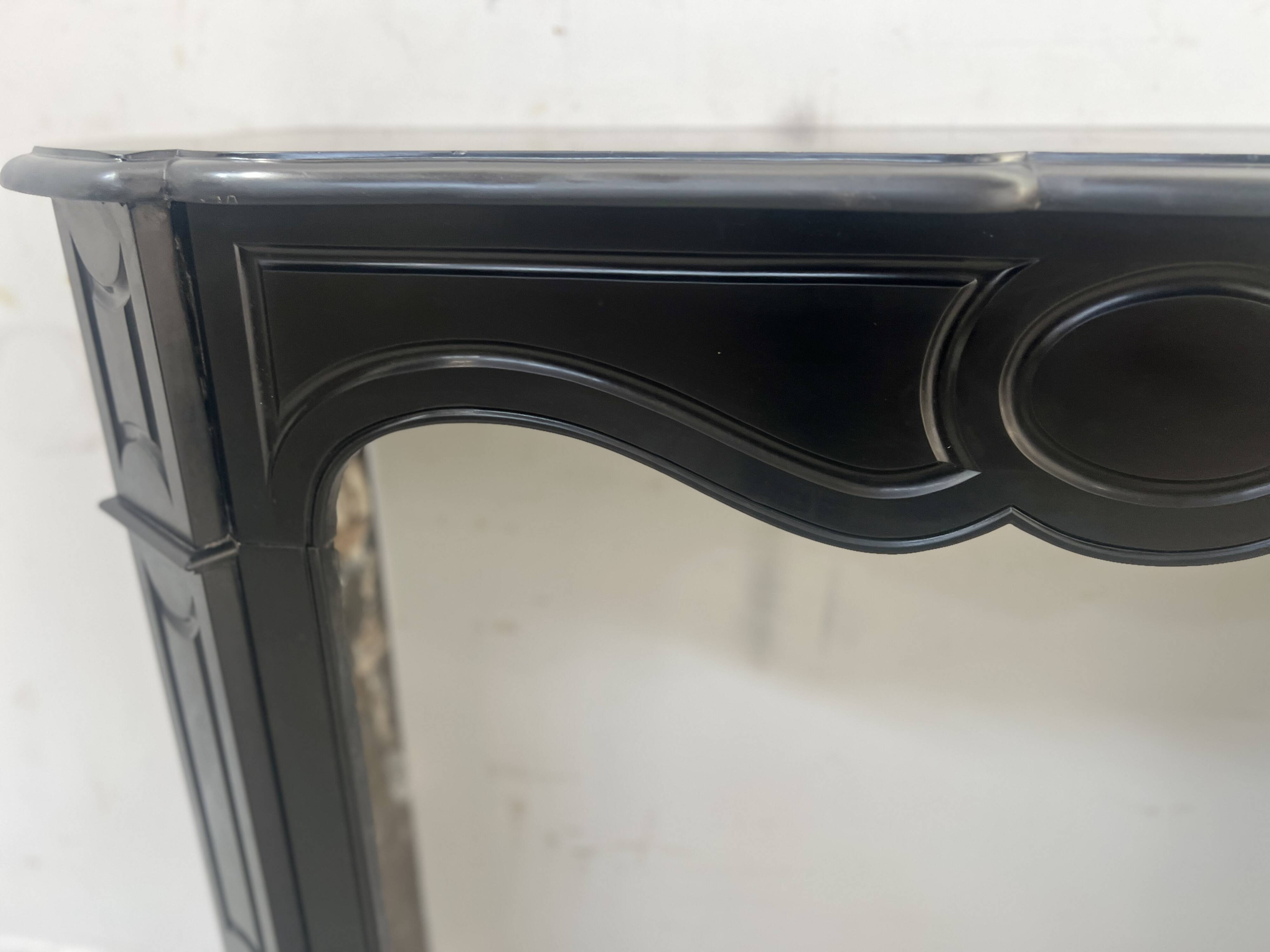 Cheminée de style Louis XV modèle Pompadour en marbre noir moucheté, XXe siècle