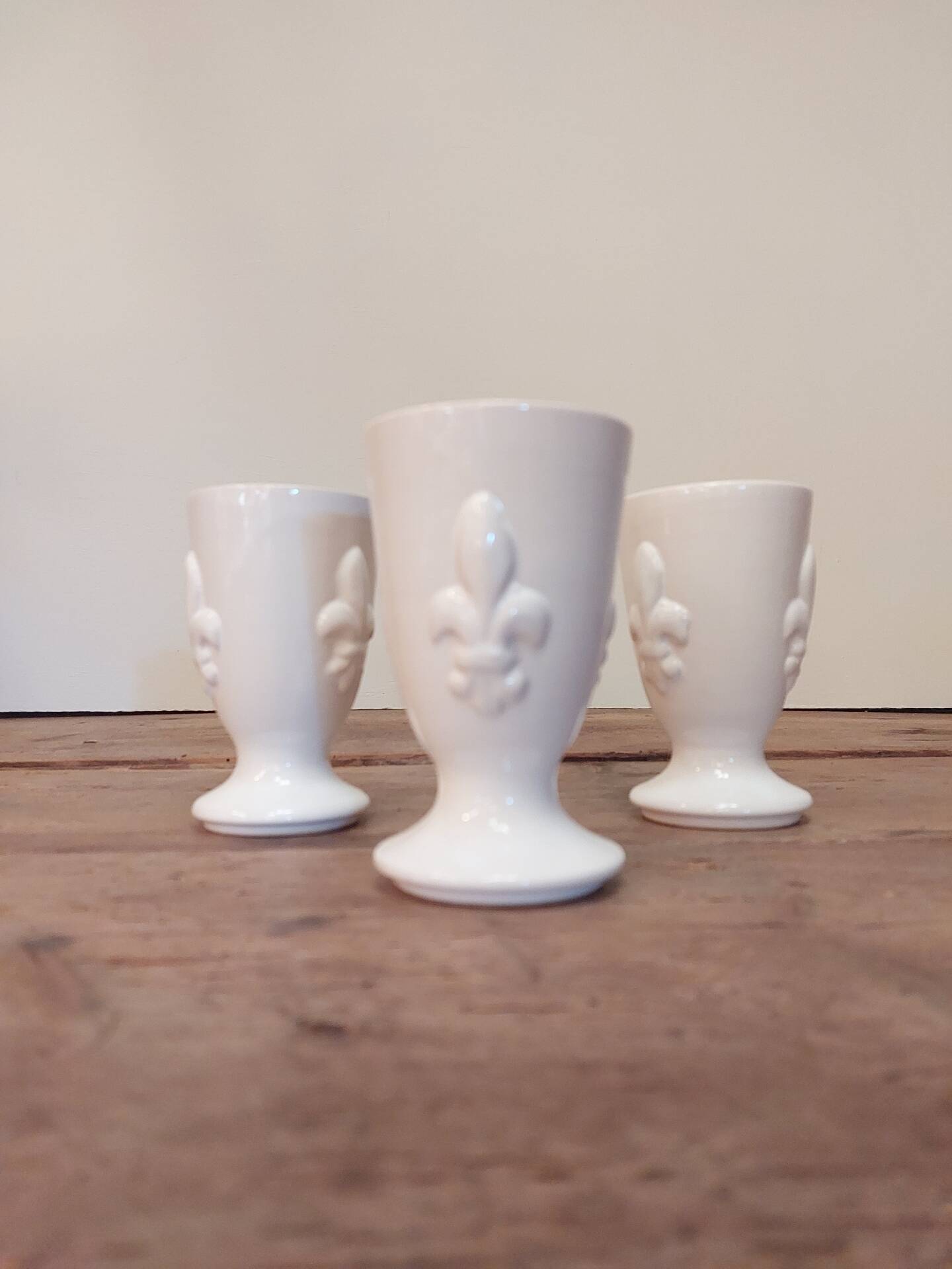 Three antique cups decorated with fleur-de-lis.