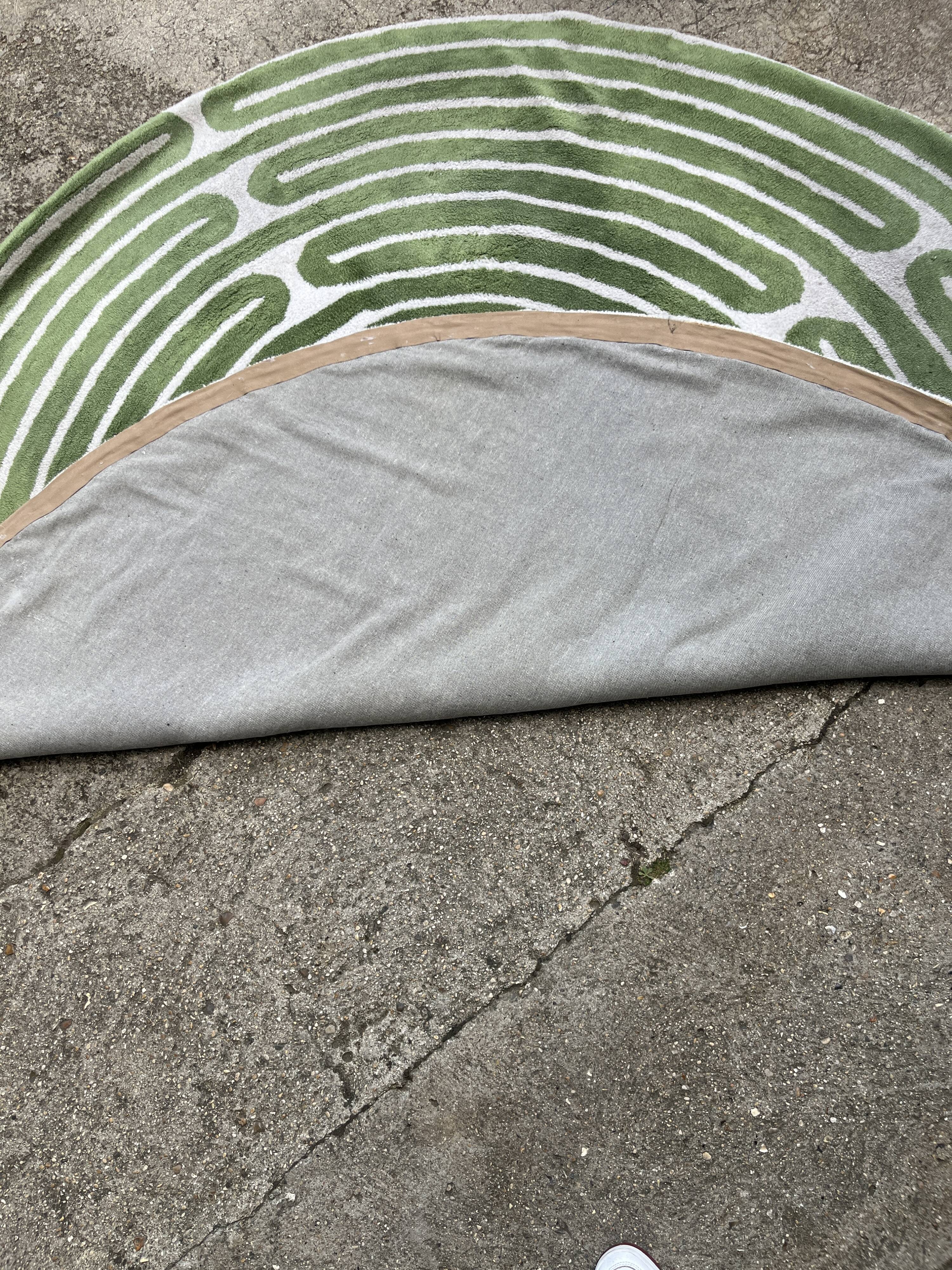 Circular rug with green decor on a cream background from the Labyrinth.