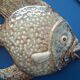 Vallauris ceramic wall sculpture of a relief fish on a blue plaque.