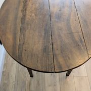 Antique wooden folding table with a patina and brass wheels.
