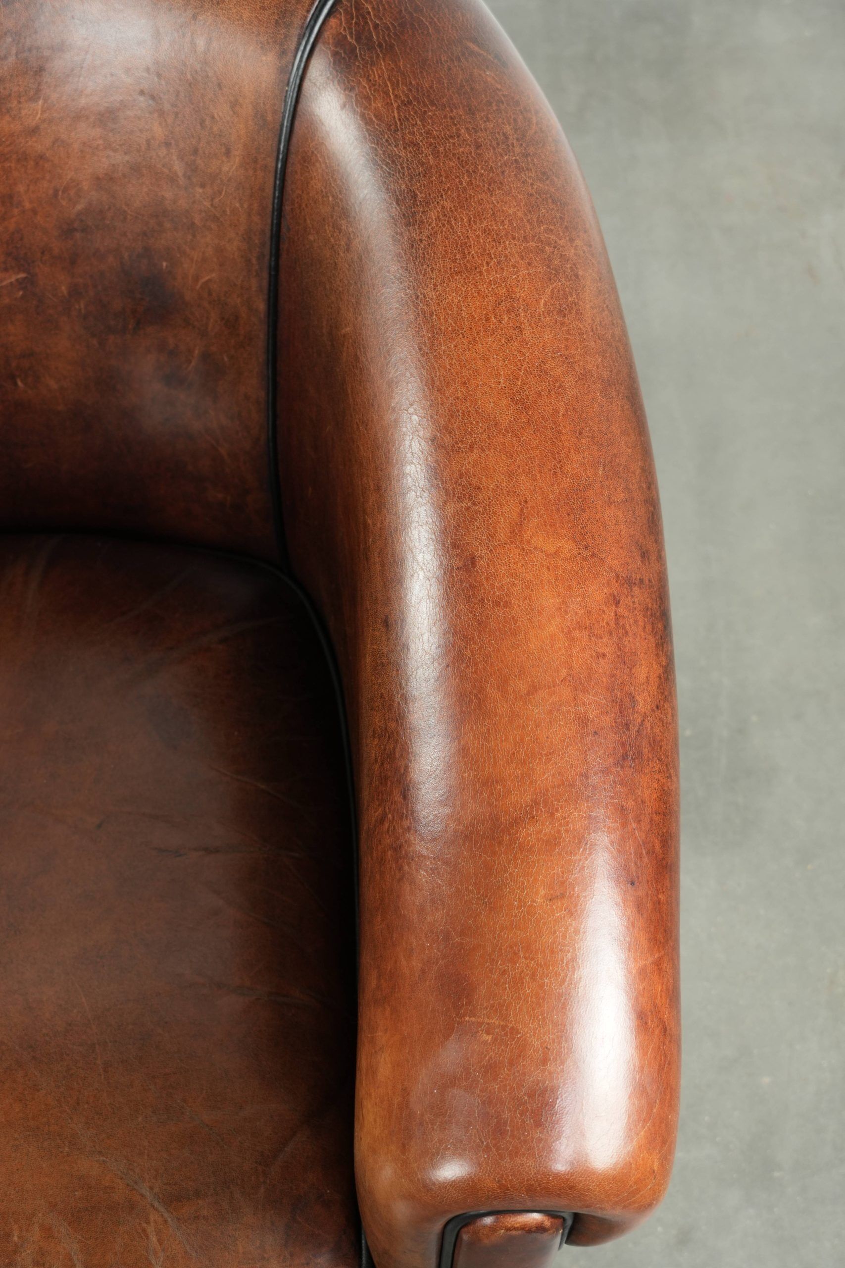 Sheepskin club armchair with deep warm colours and black piping