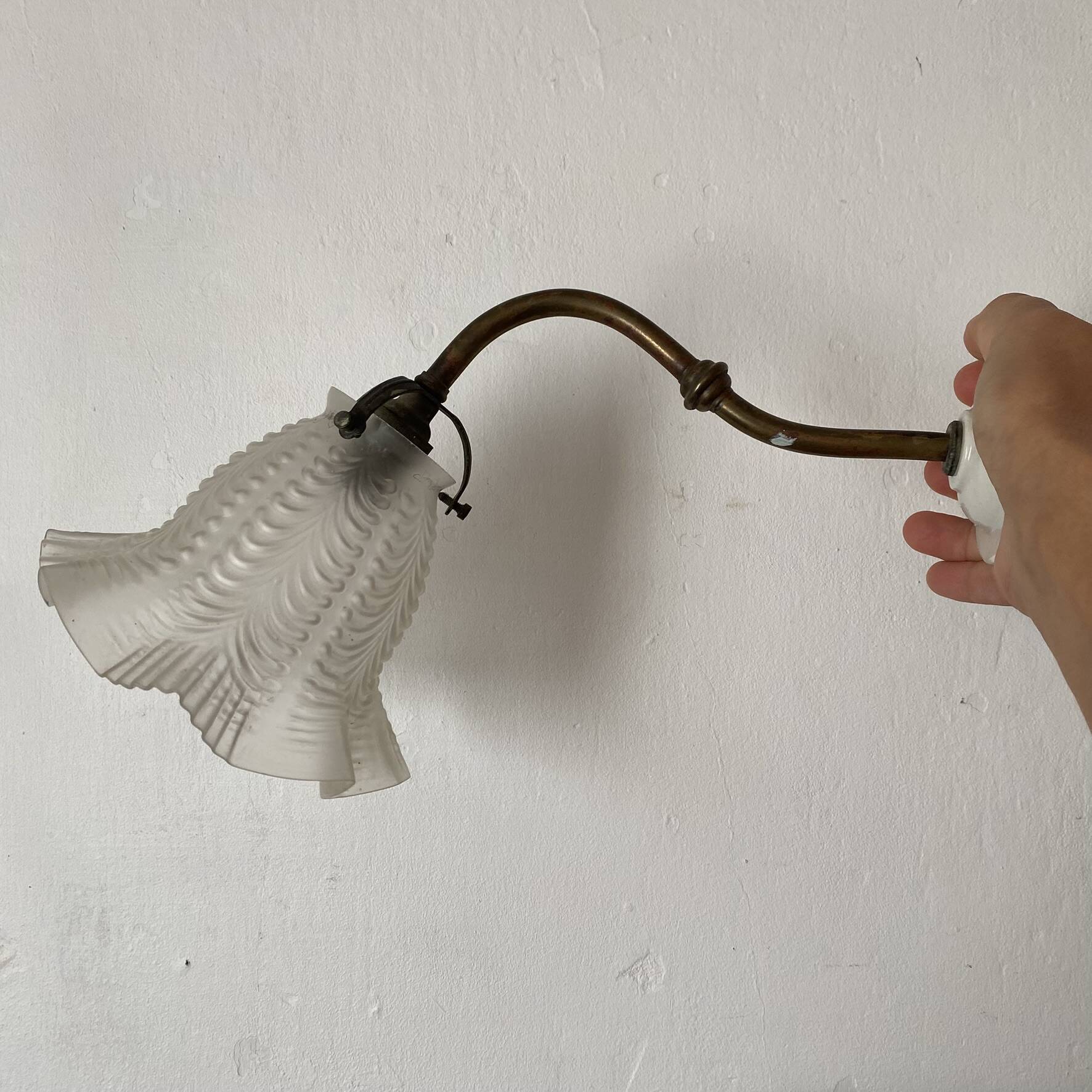 Antique swan neck wall light in brass and porcelain with a glass shade.