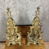 pair of Empire period dolphin firedogs in gilded bronze
