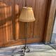 Art Deco floor lamp in bronze metal with a straw yellow fabric shade, twisted shaft, and tripod base.