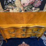 Large bow-fronted chest of drawers in blonde cherry with bronze ornamentation.