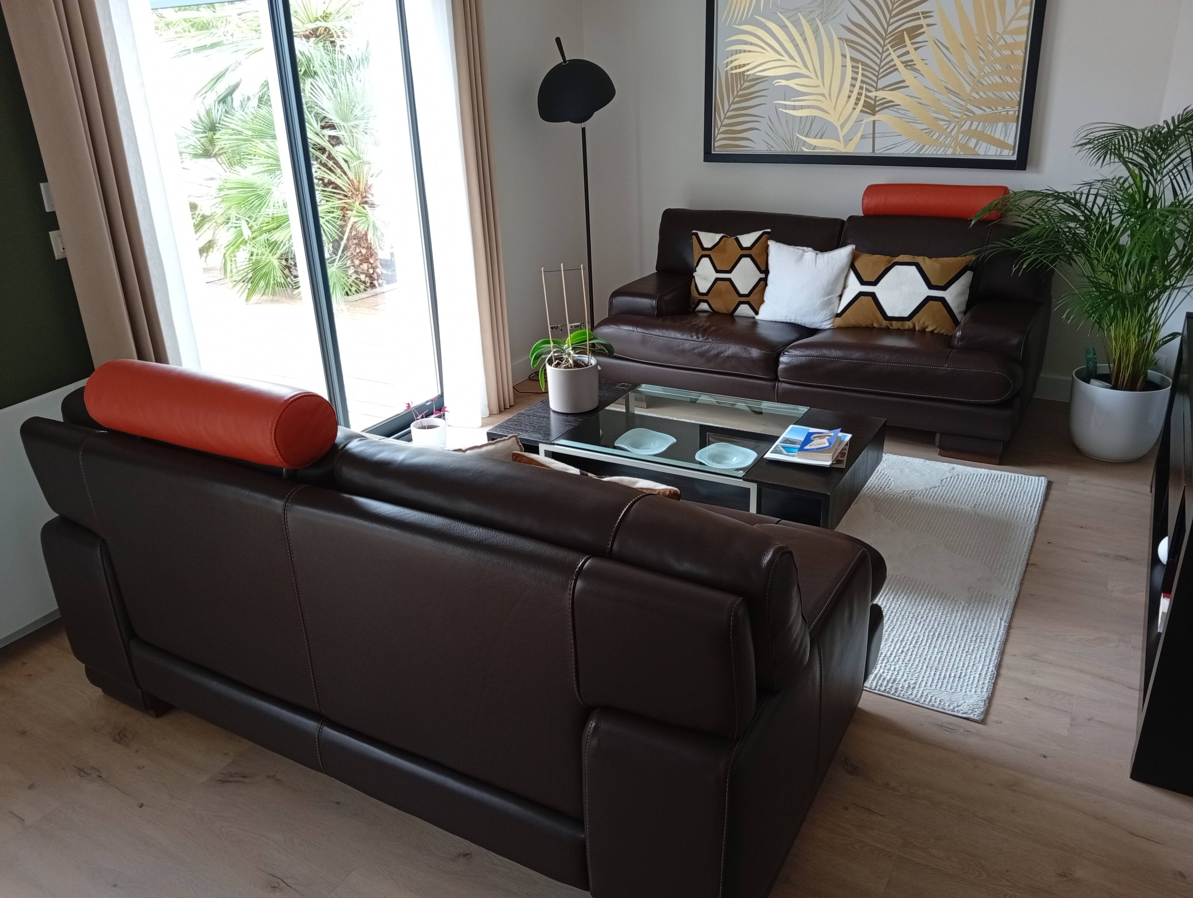 Two brown leather Crozatier two-and-a-half-seater sofas.