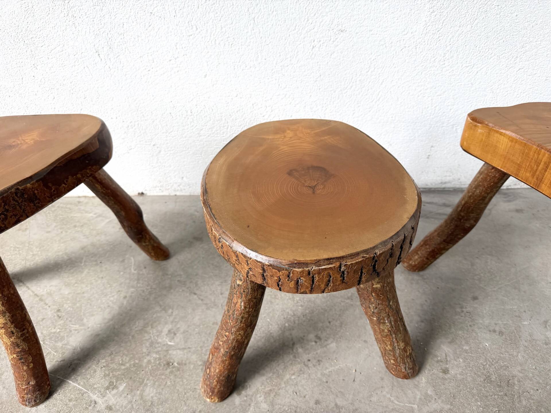 Set of three rustic solid wood tripod stools.