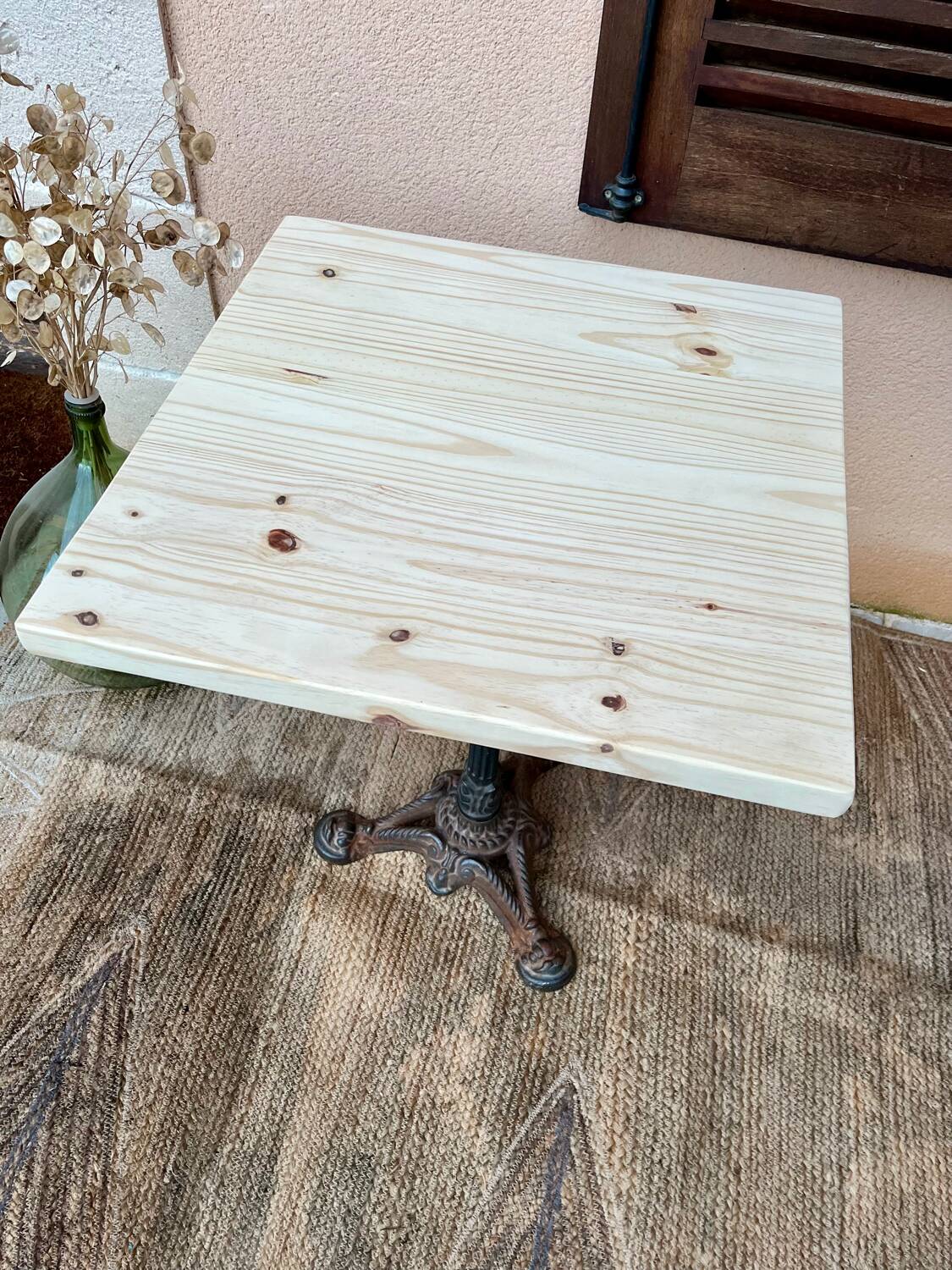 Bistro table with a raw wood top and a central cast iron base.