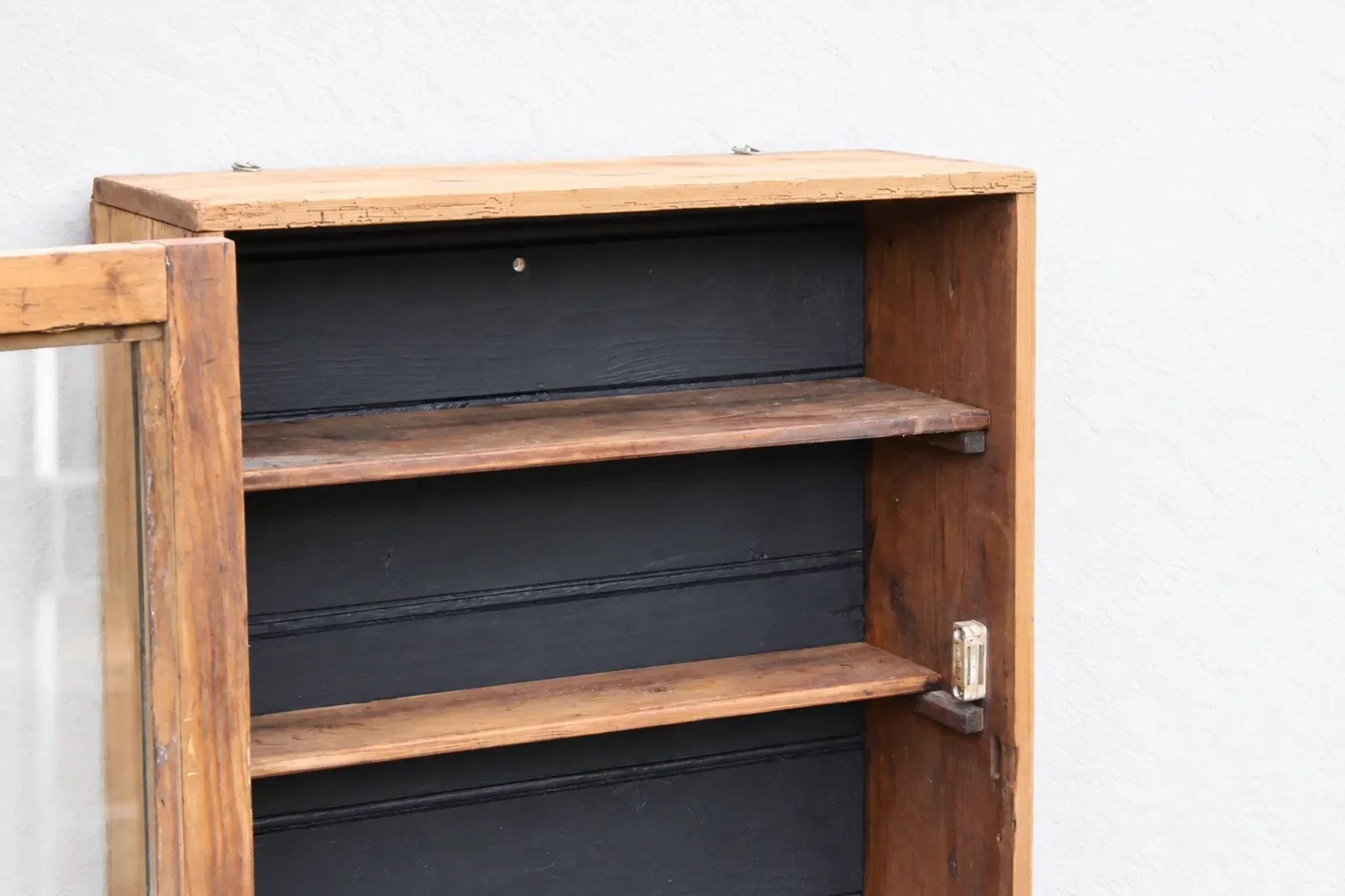 Antique wall display cabinet in natural wood and black – small glass-fronted collector's piece.