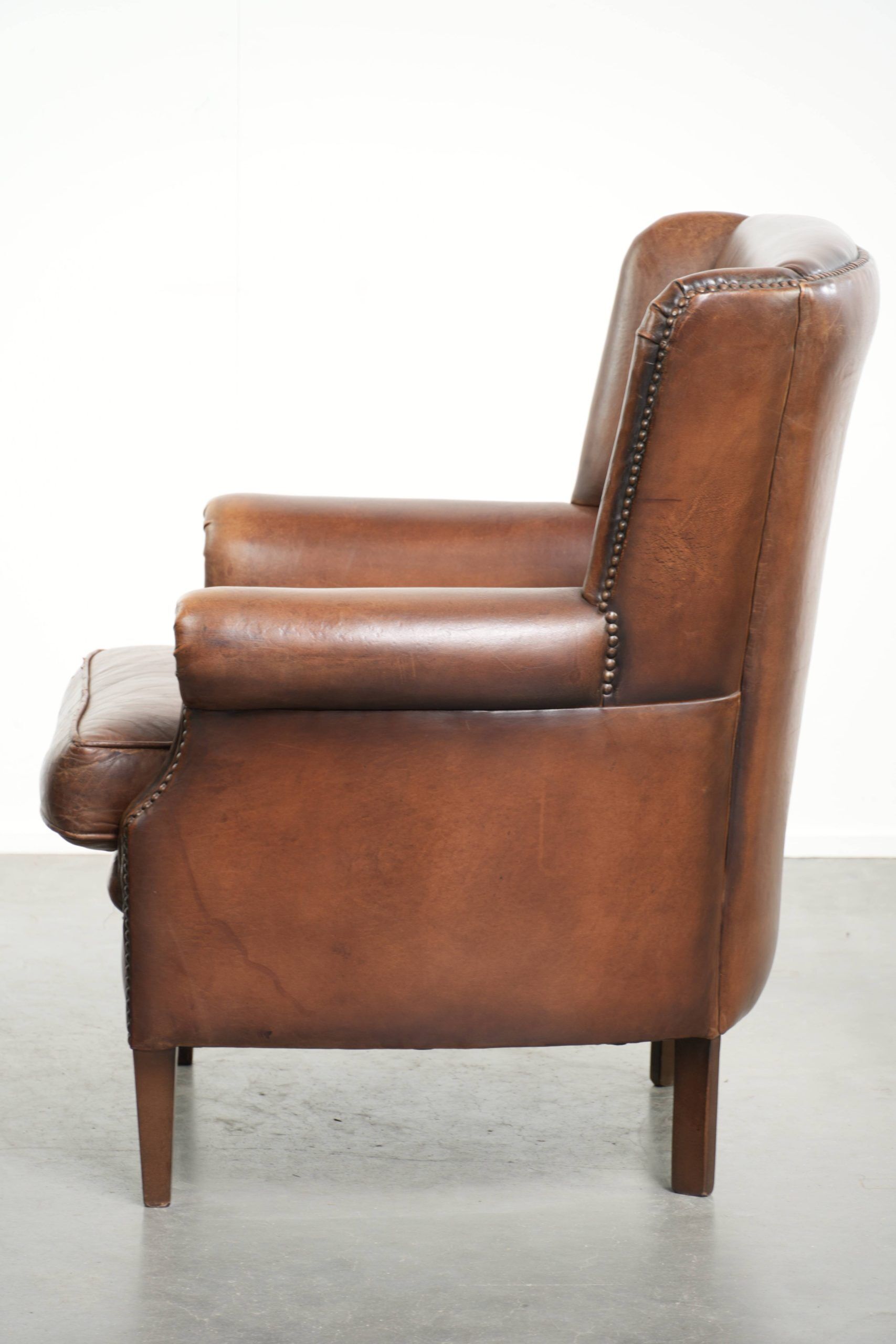 Subtle dark brown sheepskin wingback armchair with a timeless look subtle