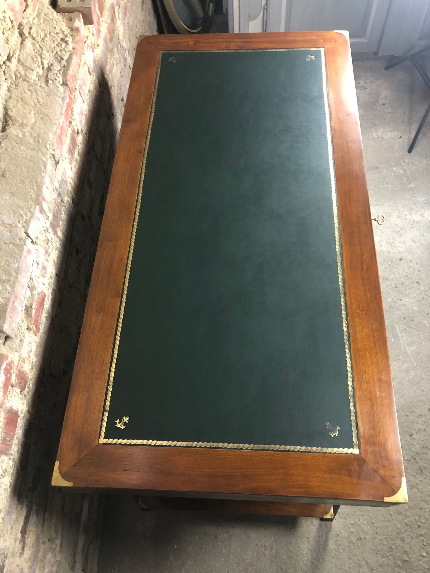 Walnut desk with green leather top resting on two trestles