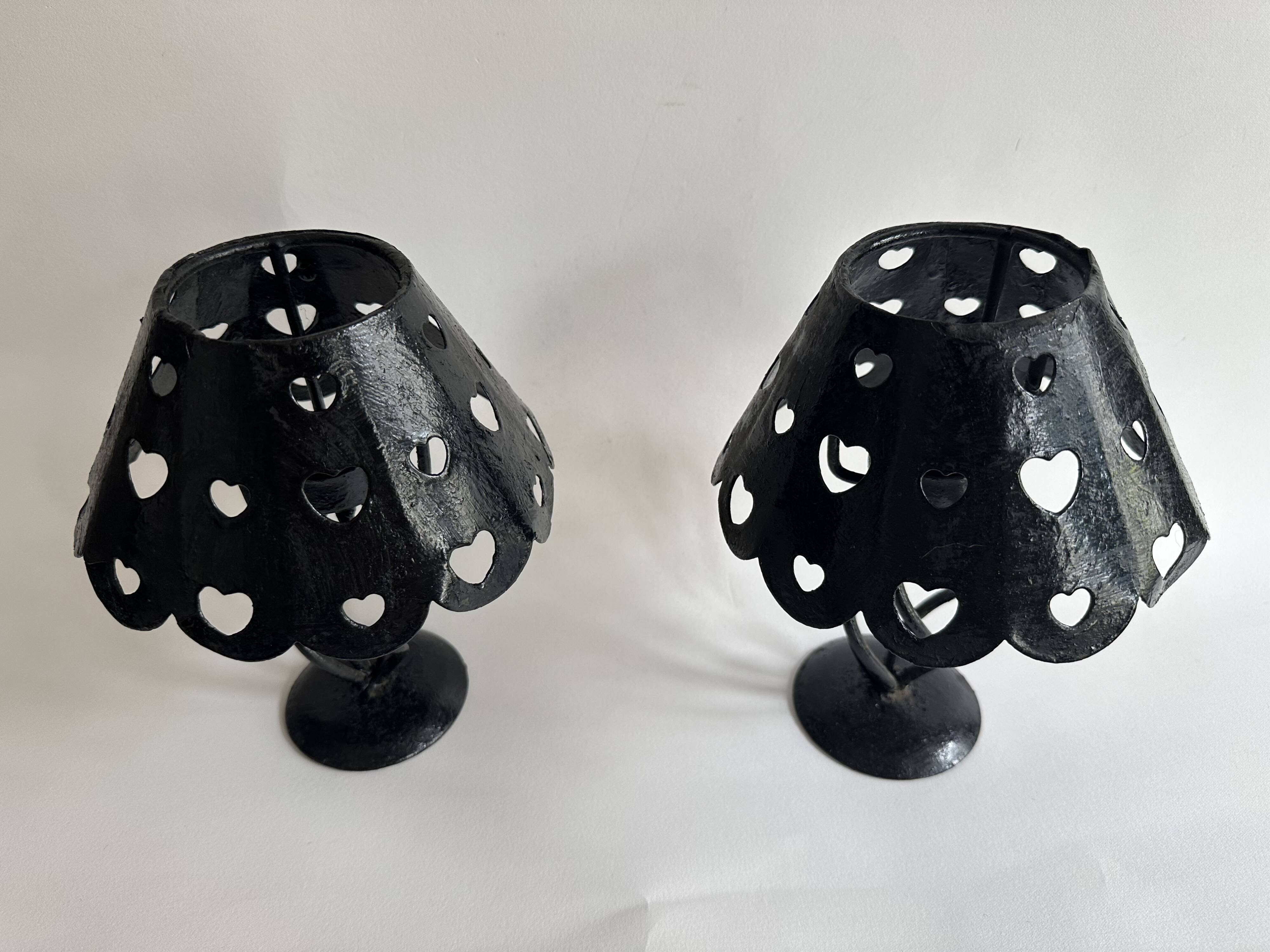 Pair of black wrought iron lanterns with heart patterns, romantic style.