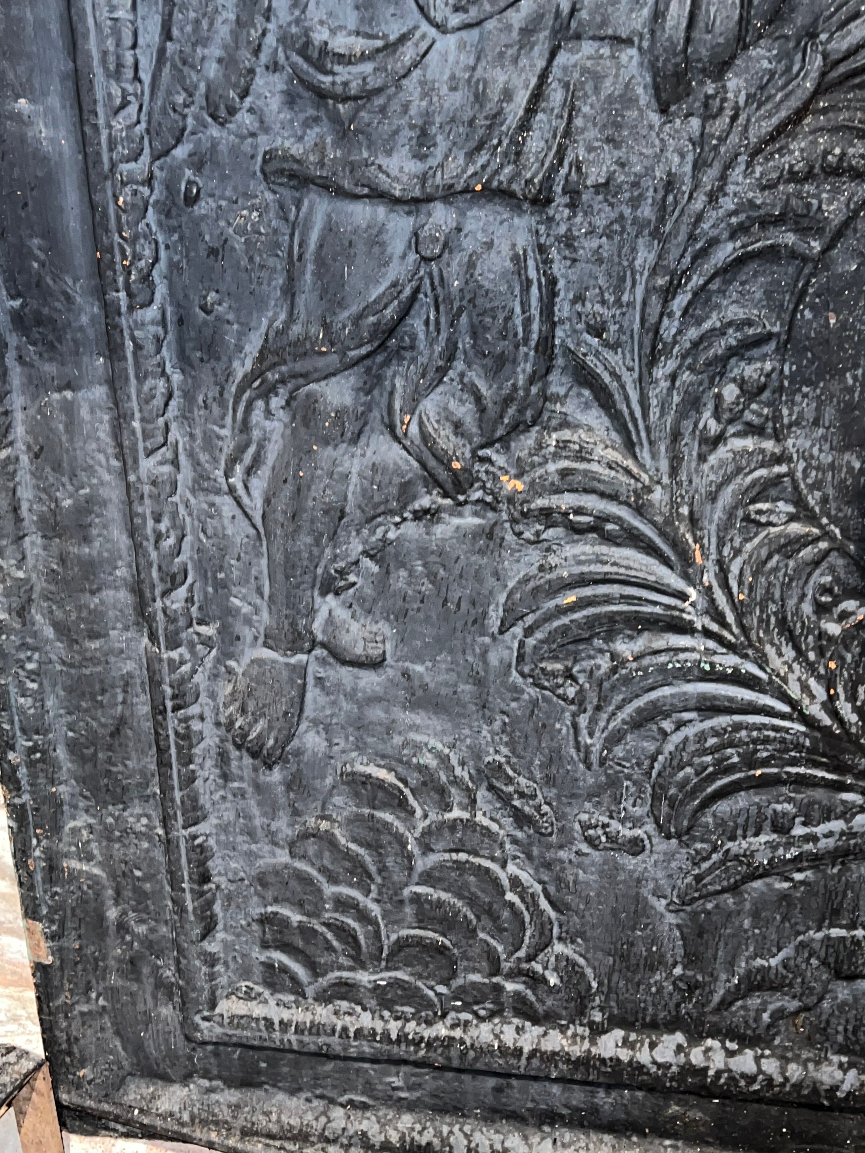 huge old fireplace plate has decoration of angels, crown and fleurs-de-lis