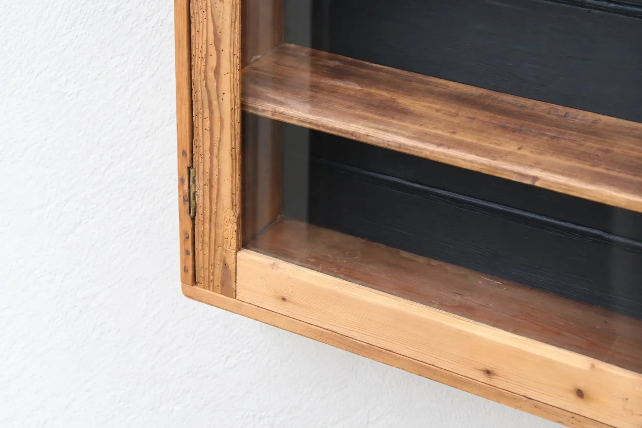 Antique wall display cabinet in natural wood and black – small glass-fronted collector's piece.