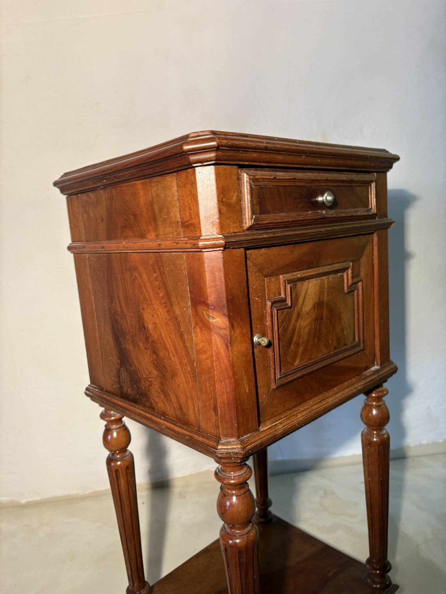 Antique wooden bedside table with turned legs.