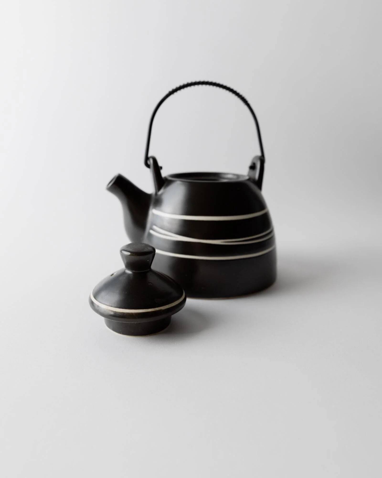 Vintage ceramic teapot from the 1980s, black with white stripes and a metal handle.