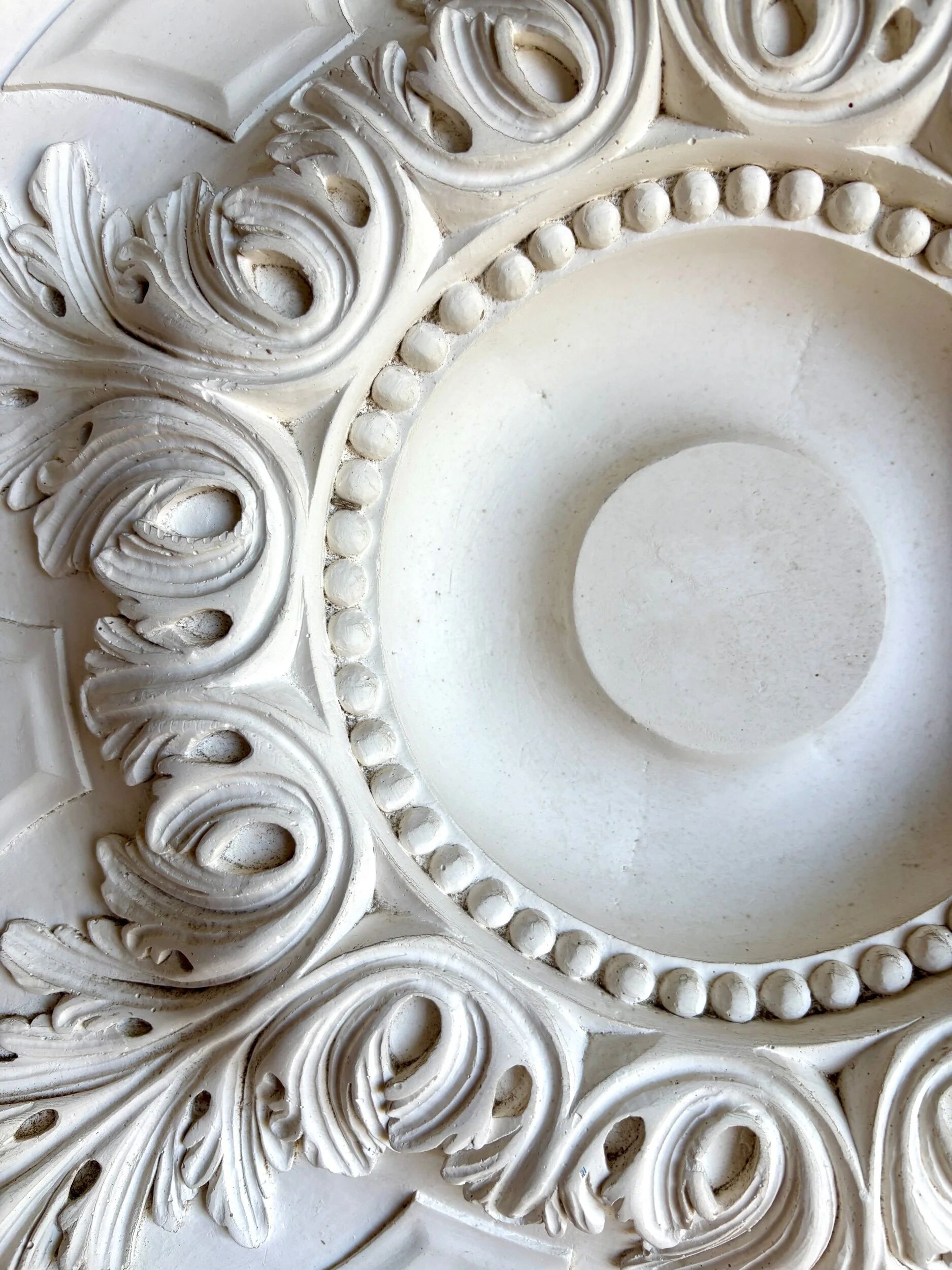 Rosette on white background, decorated with scrolls and beaded frieze ⌀ 61 cm