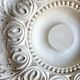 Rosette on white background, decorated with scrolls and beaded frieze ⌀ 61 cm
