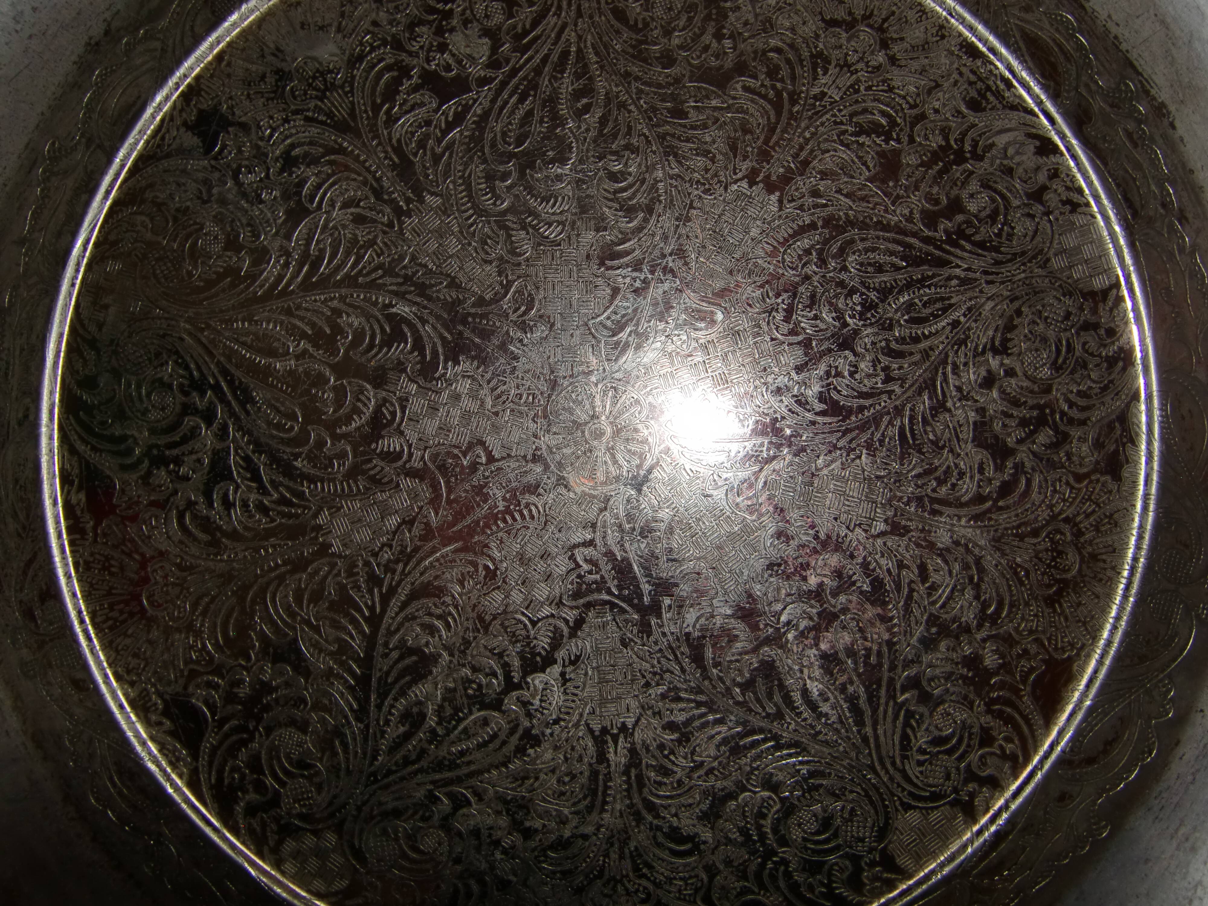 Large silver metal tray raised by a central foot