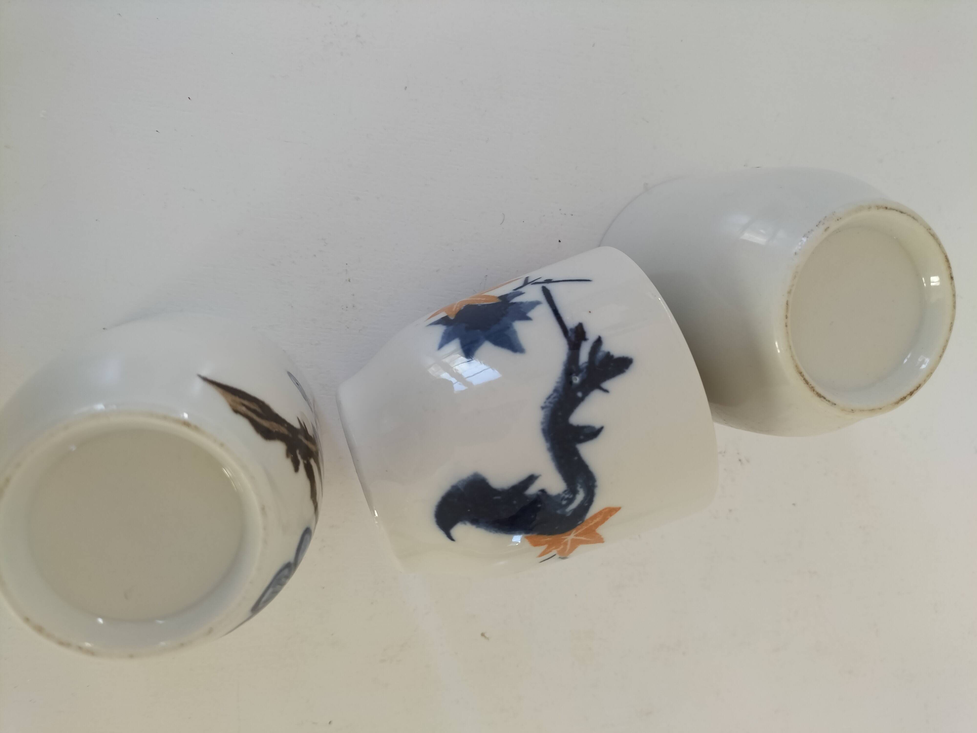 Set of three hand-painted porcelain cups with floral patterns.