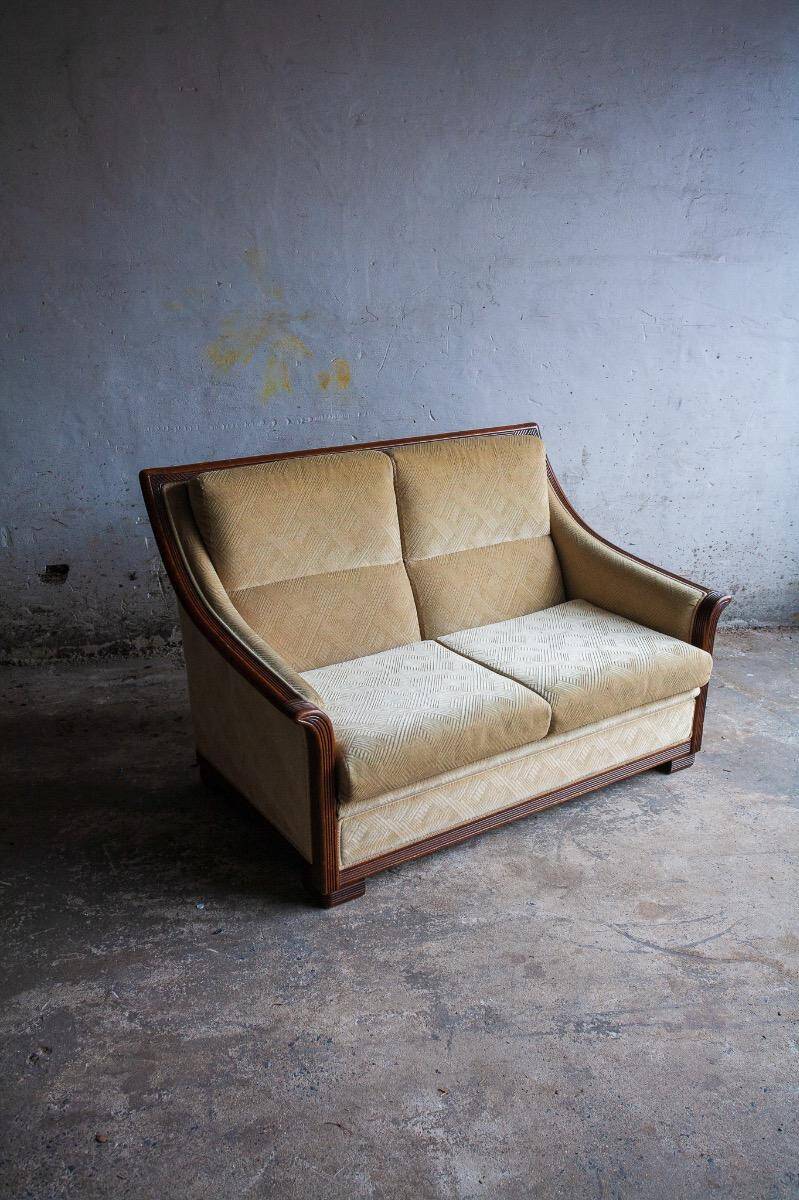 Two-seater Art Deco sofa with ornate wooden details.