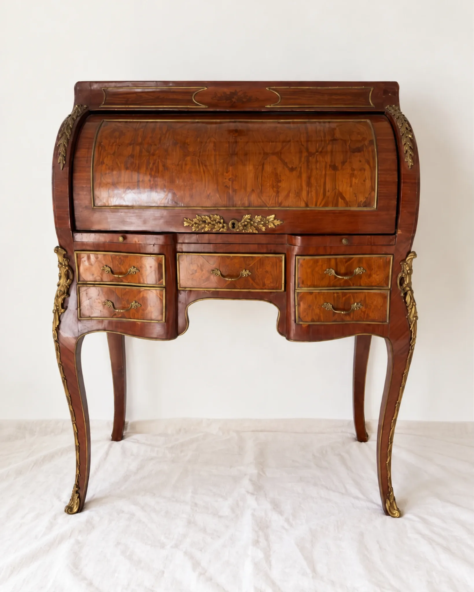 Louis XV cylinder desk with floral marquetry and gilded ornaments.