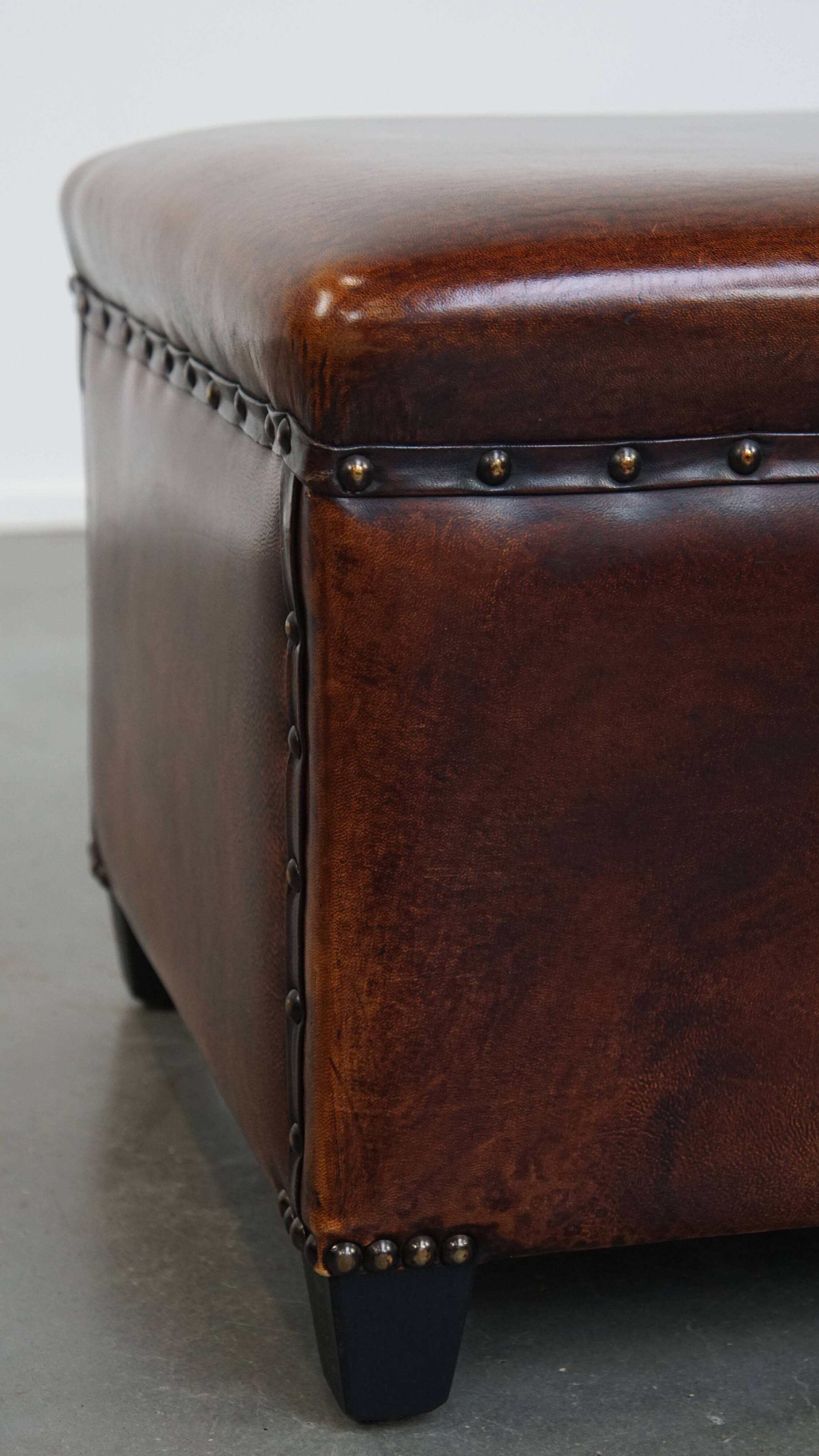 Cognac-colored sheepskin stool with decorative studs