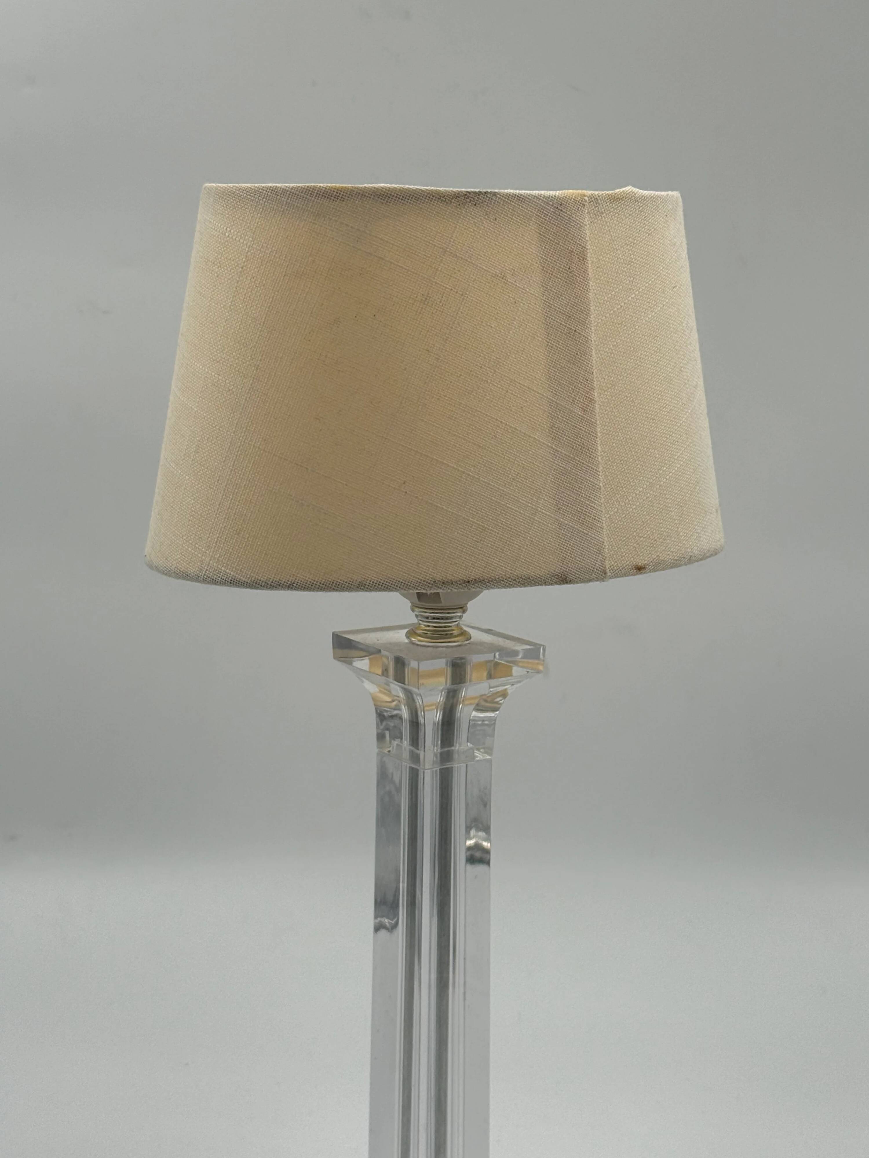 Modern table lamp in plexiglass with fabric shade.