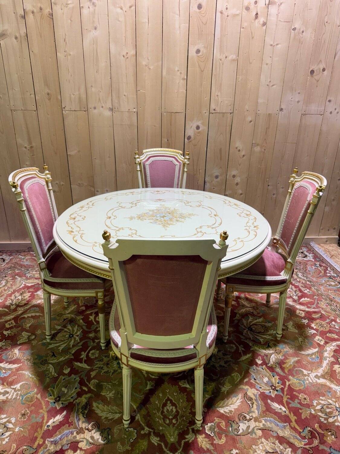 Louis XVI dining room table set with painted wood, gold accents, and pink velvet.