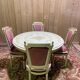Louis XVI dining room table set with painted wood, gold accents, and pink velvet.