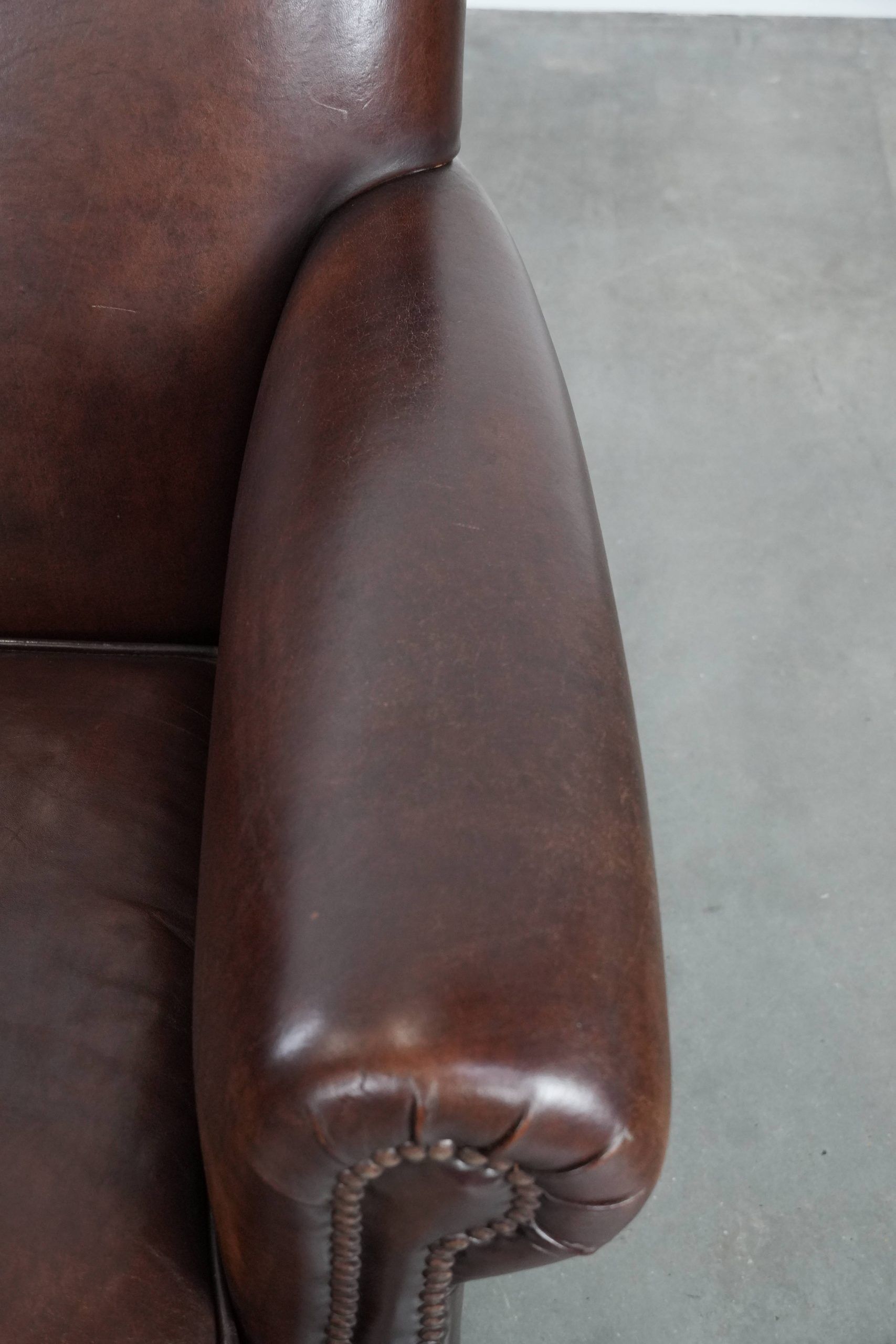 Sheepskin armchair with a classic finish and decorative studs.