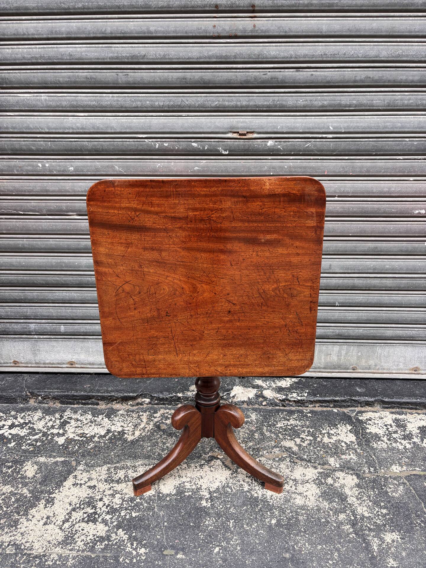 19th-century solid mahogany table with a tilting top and brass mechanism.