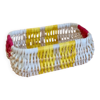 Vintage woven basket in yellow, white, and pink plastic.