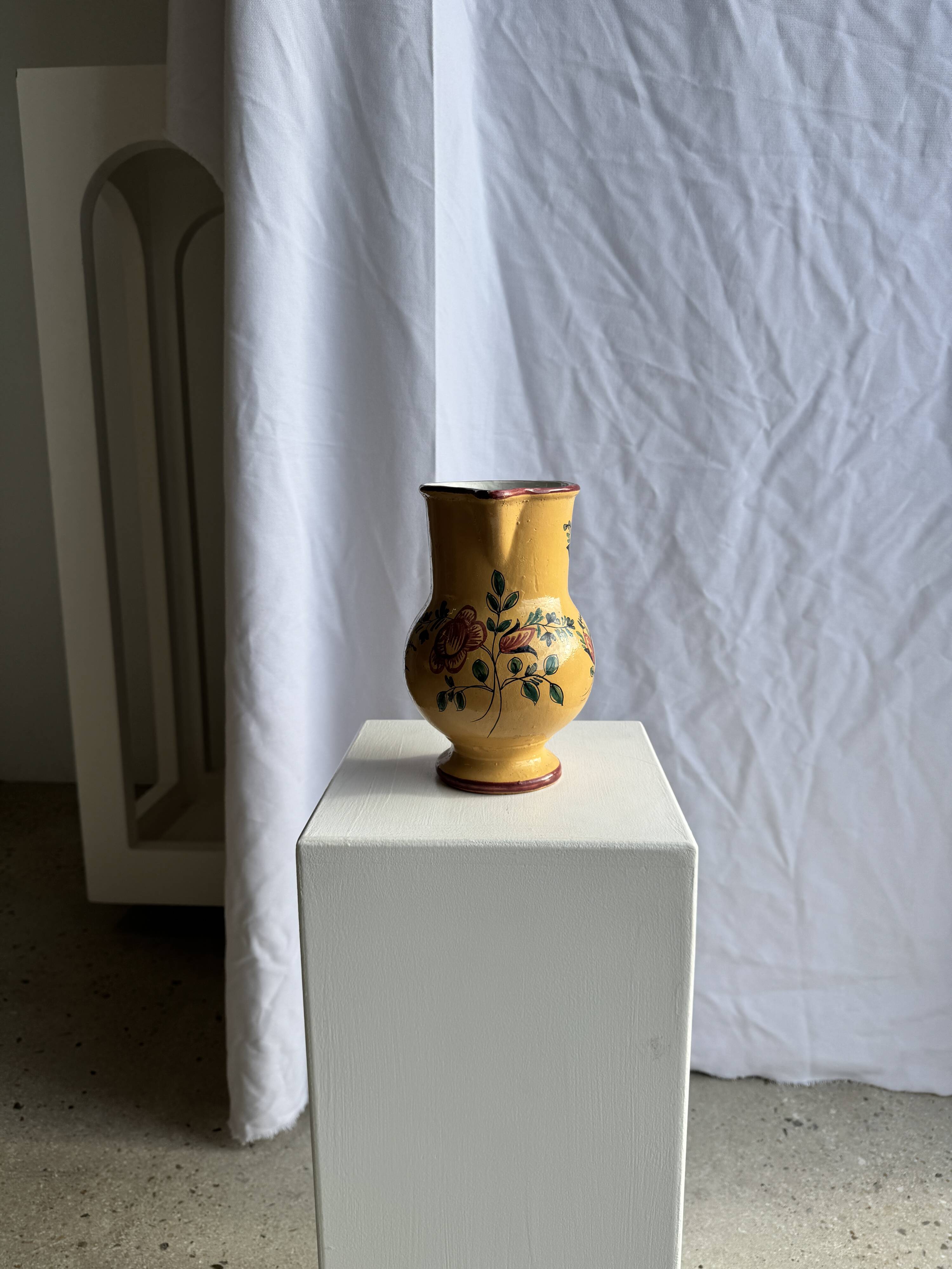 Large antique handmade ochre yellow jug with a pink flower pattern.