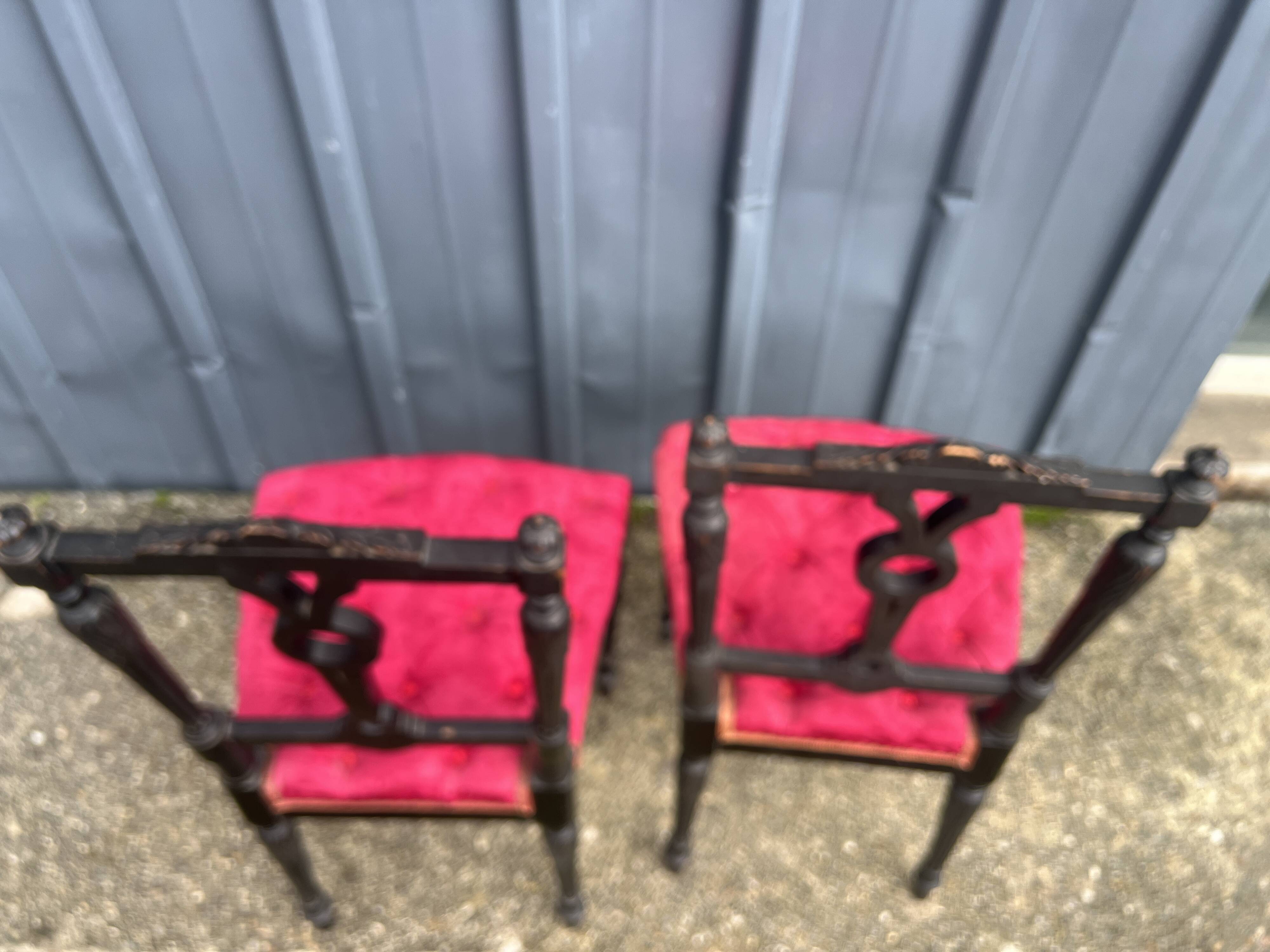 Pair of black lacquered chairs with purple tufted upholstery.