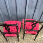 Pair of black lacquered chairs with purple tufted upholstery.