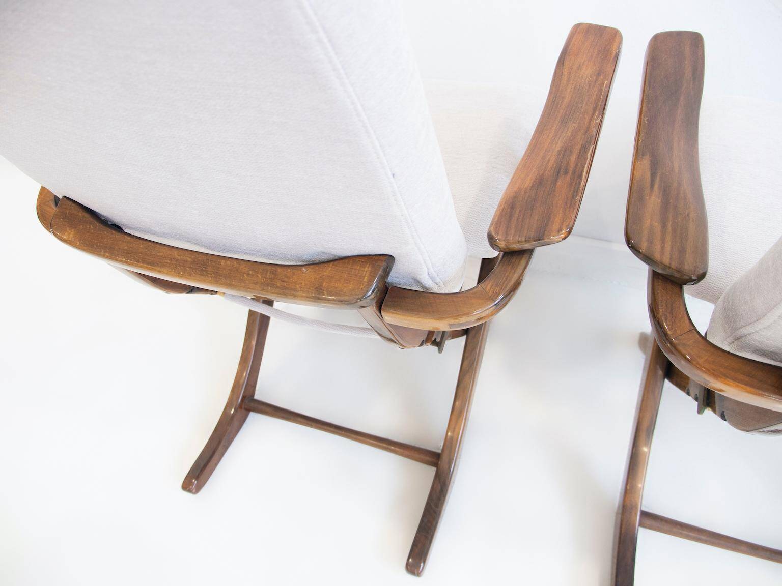Pair of varnished wooden reclining armchairs, upholstered in lightweight fabric.