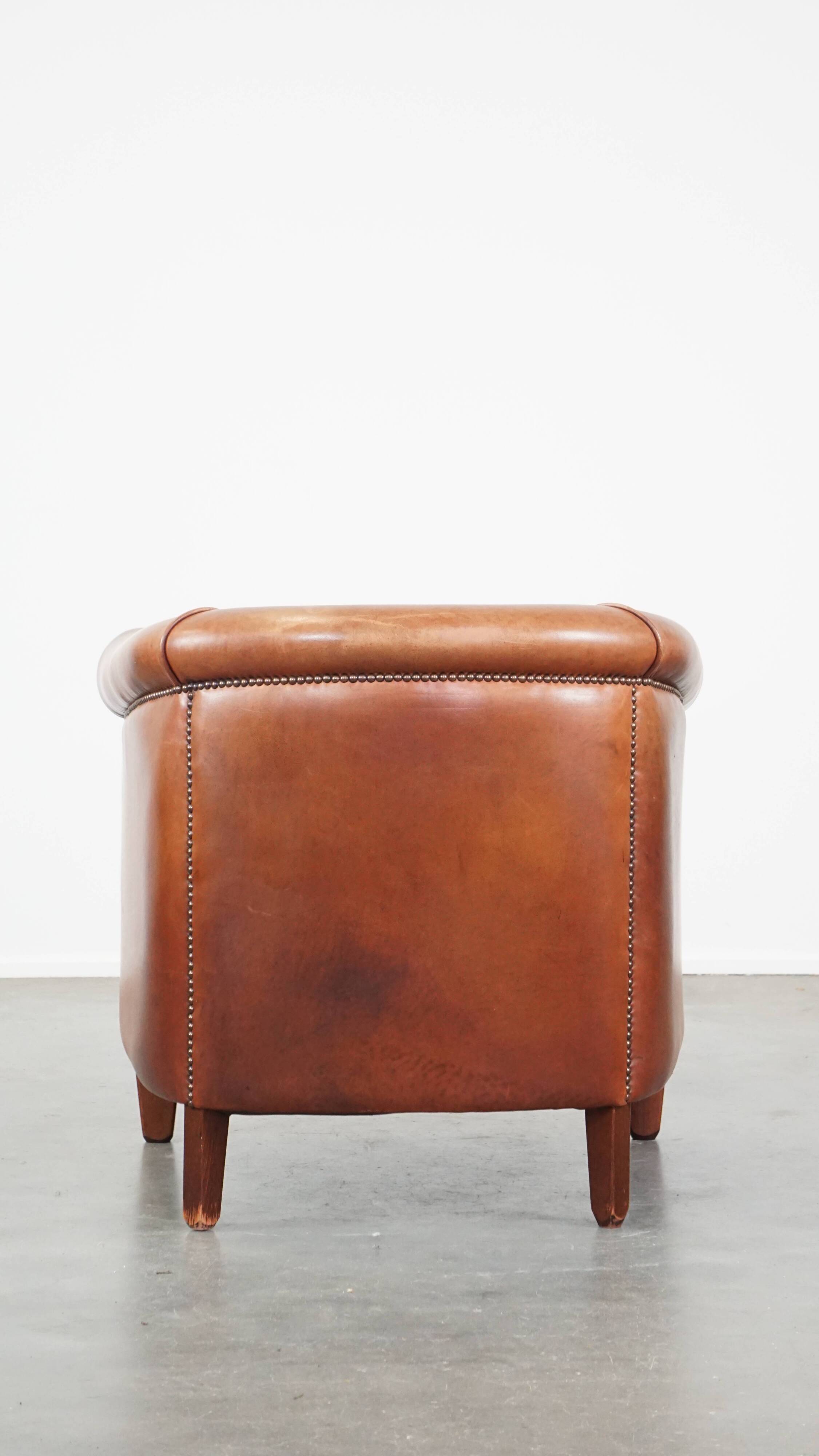Cognac-colored cow leather club chair finished with decorative nails in English style