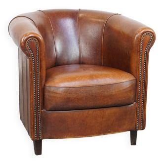 Fauteuil club en cuir de mouton de couleur cognac et finition passepoilée