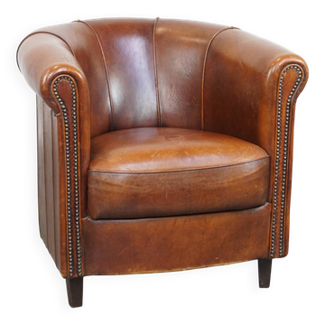 Sheep leather club chair in a cognac color and finished with piping