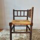 Old wooden turned spindle fireside chair with a straw seat.