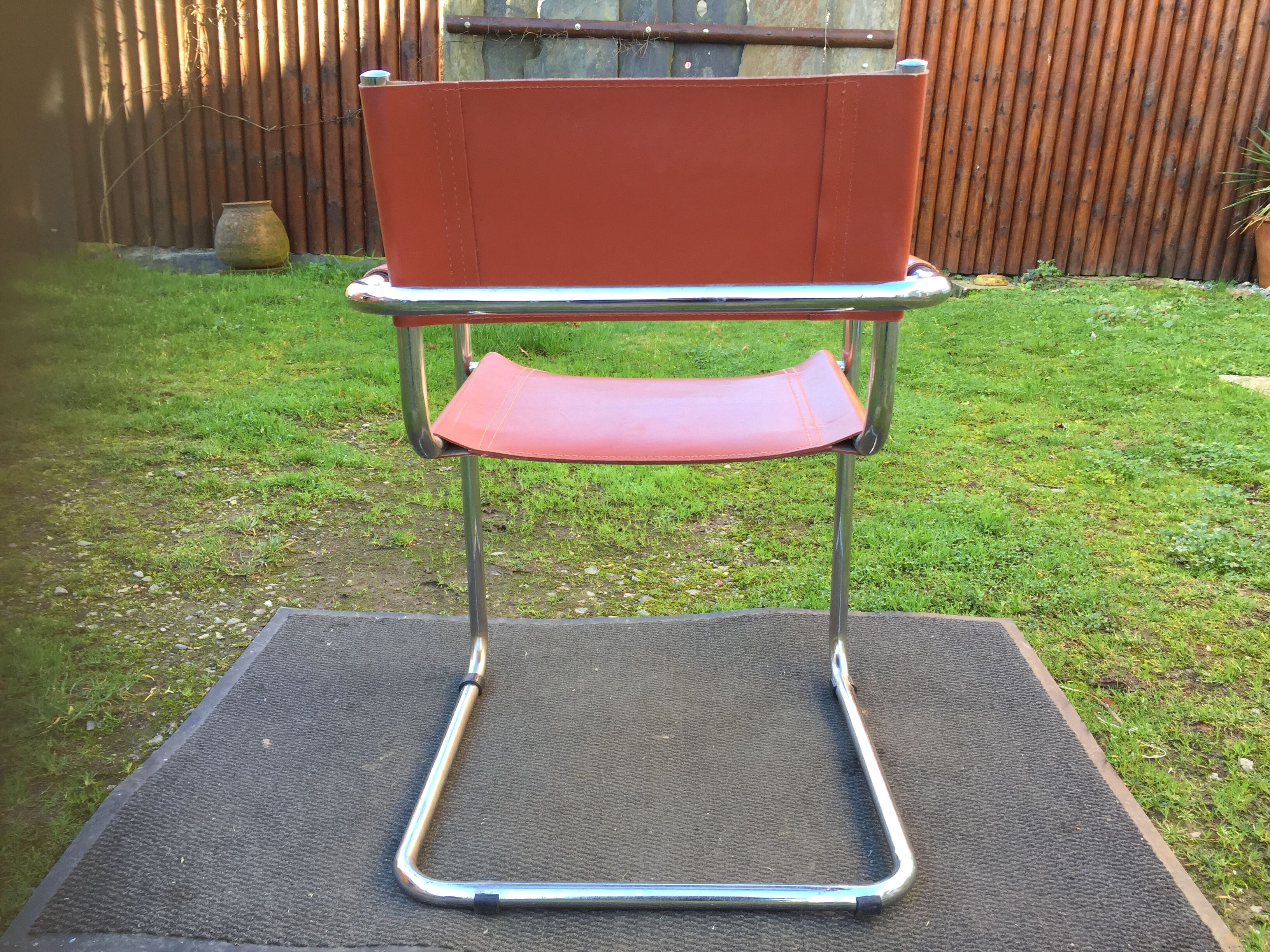 Design armchair with base in chrome tubular steel and seat in brown leather