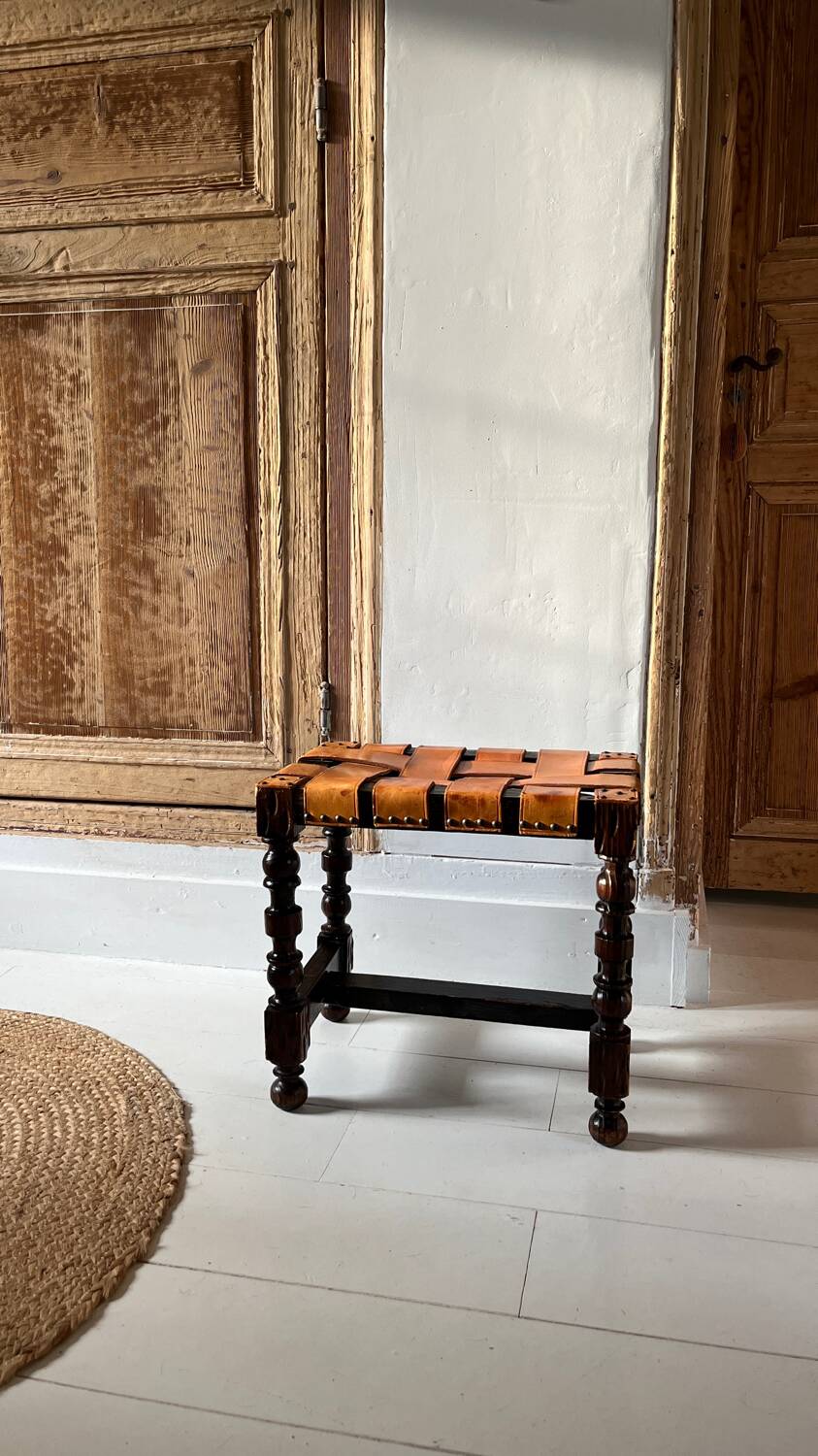 Antique turned wooden stool with woven leather.