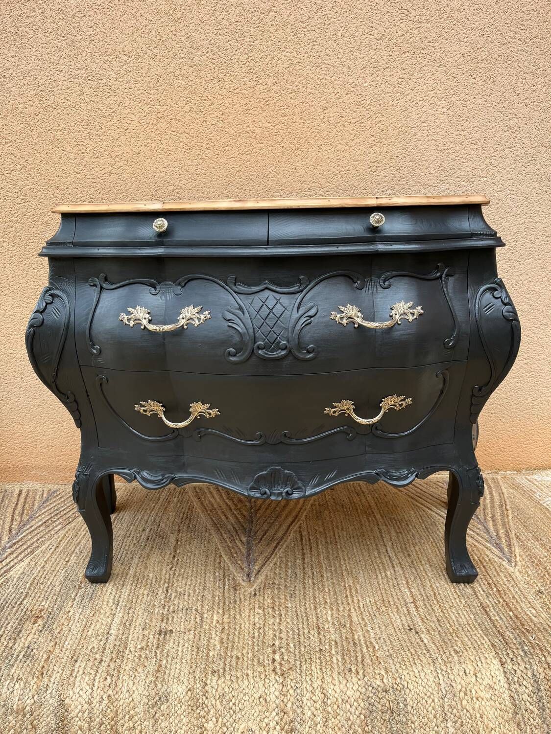 Curved commode painted in black and wood.