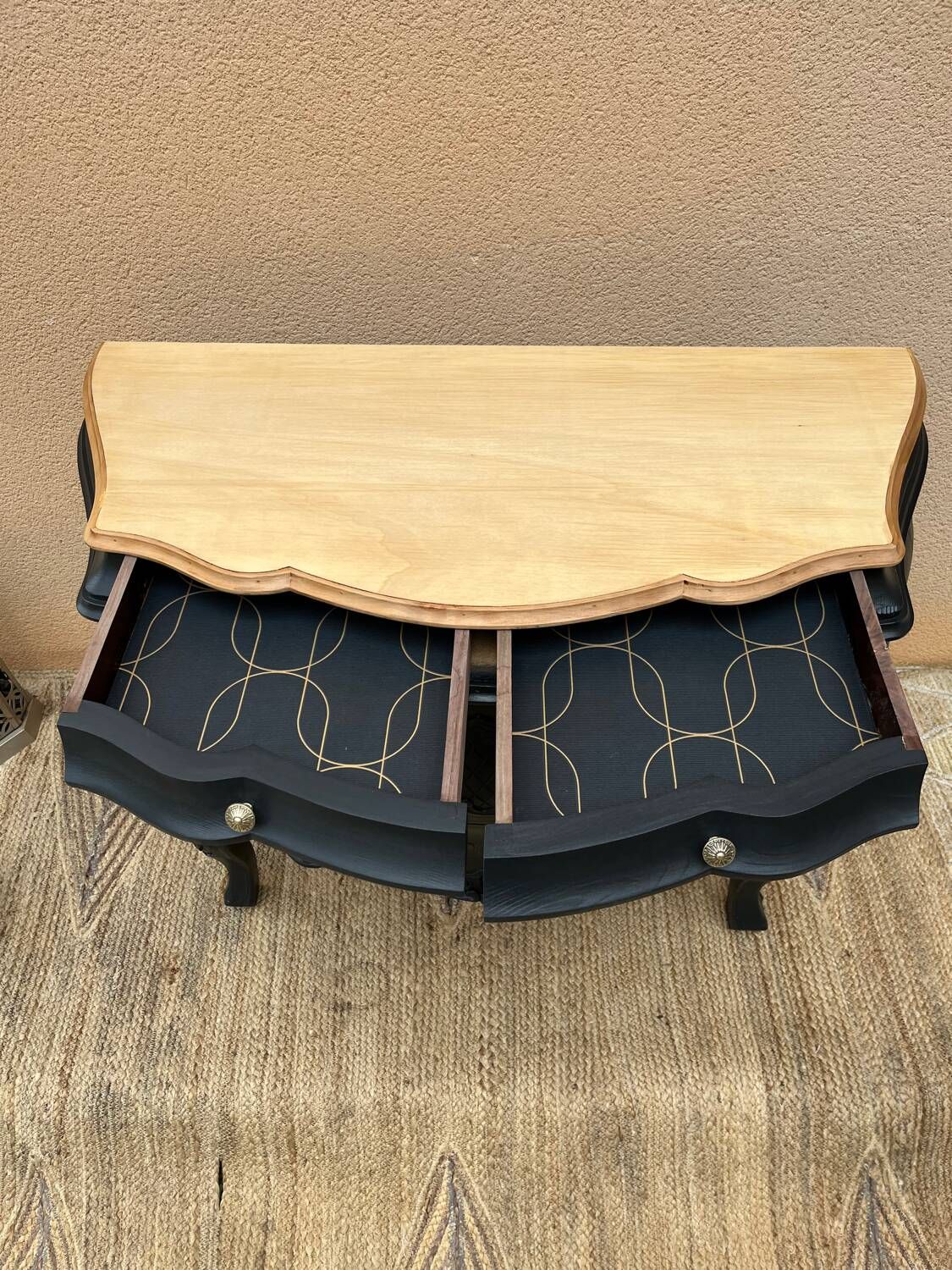Curved commode painted in black and wood.