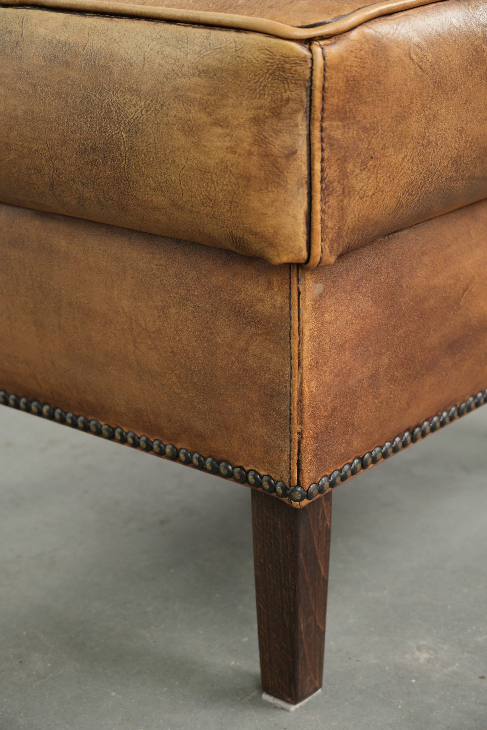 Cowhide ottoman with a beautiful patina finished with decorative nails